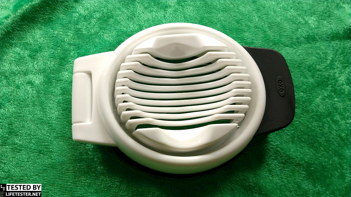 Image description: The picture displays the OXO Grip egg slicer from a top view, showcasing its oval shape, cutting wires, and non-slip grip handle.