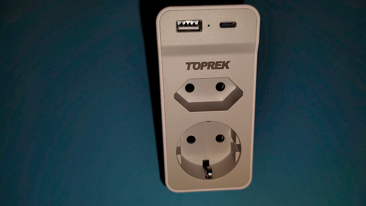 Der TOPREK Doppelstecker in der Frontansicht mit USB-A und USB-C Port oben sowie Euro- und Schuko-Steckdose darunter.